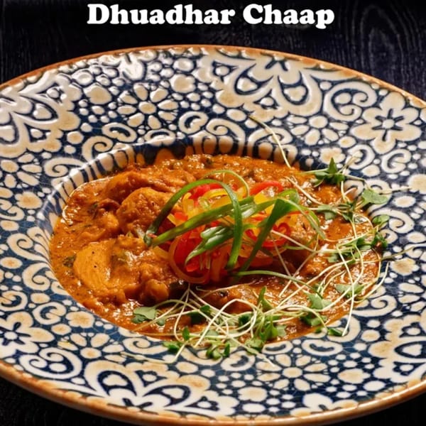 Nirmanz Food Boutique's Dhuaadhar Chaap, an Indian dish, served in a decorative blue and white bowl.