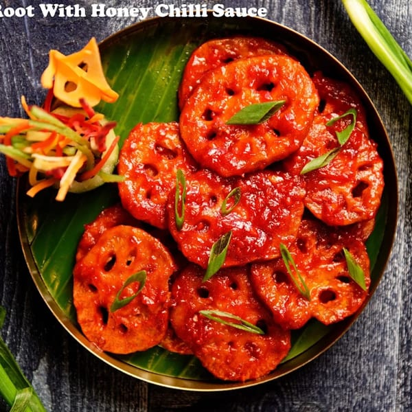 Nirmanz Food Boutique's Honey Chilli Lotus Root, a vibrant Indian dish with green garnish and side salad.